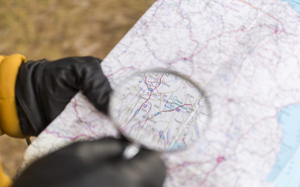 crop hands with magnifying glass reading map