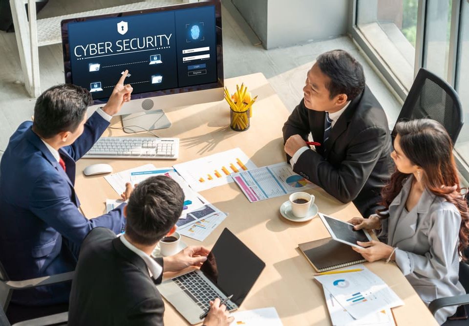 Professionals reviewing cybersecurity data, applying ISO 27001 for data security in a tech firm in Malaysia.